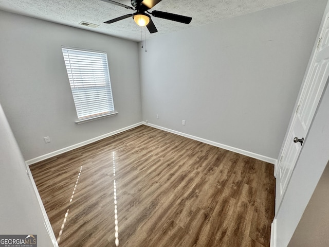 empty room featuring ceiling fan, dark hardwood / wood-style flooring, and a textured ceiling