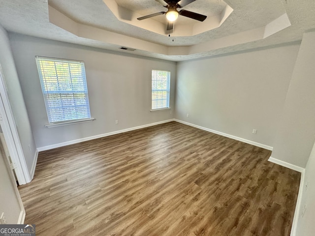 spare room with a tray ceiling, ceiling fan, and hardwood / wood-style floors