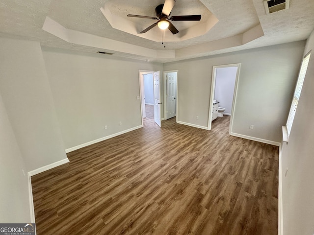 spare room featuring a raised ceiling, ceiling fan, wood-type flooring, and a textured ceiling