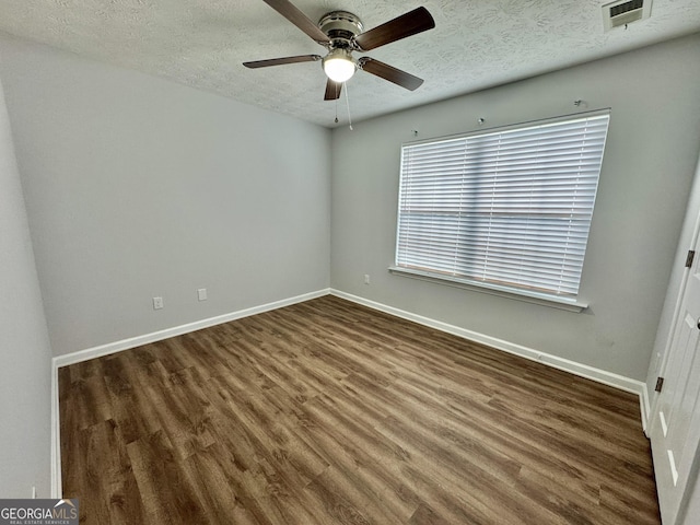 spare room with a textured ceiling, ceiling fan, and dark hardwood / wood-style floors