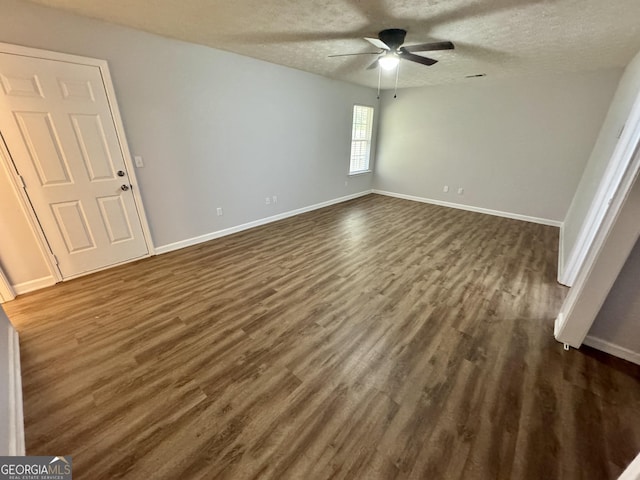 empty room with a textured ceiling, dark hardwood / wood-style flooring, and ceiling fan