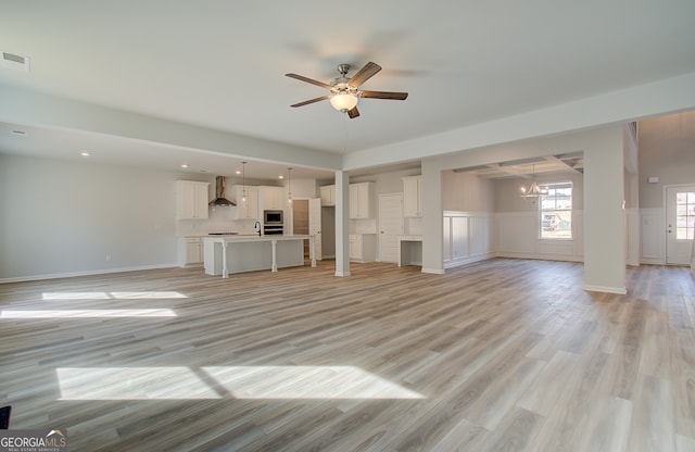 unfurnished living room with light wood-type flooring and ceiling fan with notable chandelier