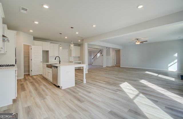 kitchen with decorative light fixtures, dishwasher, a center island with sink, sink, and white cabinetry