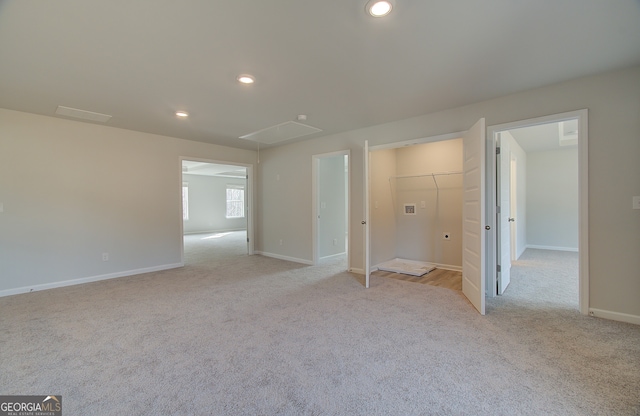 unfurnished bedroom with light carpet, a closet, and a walk in closet