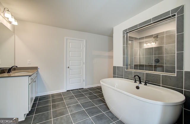 bathroom with a washtub, vanity, and tile patterned flooring