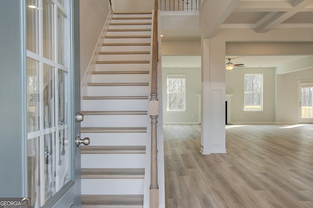 stairway featuring hardwood / wood-style flooring, plenty of natural light, crown molding, and beamed ceiling