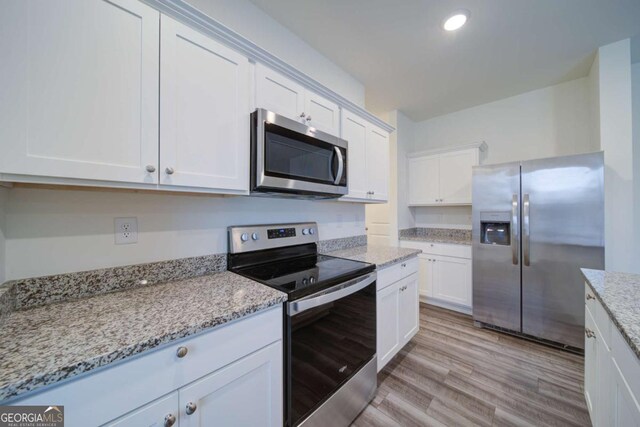 kitchen featuring light stone counters, stainless steel appliances, a center island with sink, dark hardwood / wood-style floors, and white cabinetry