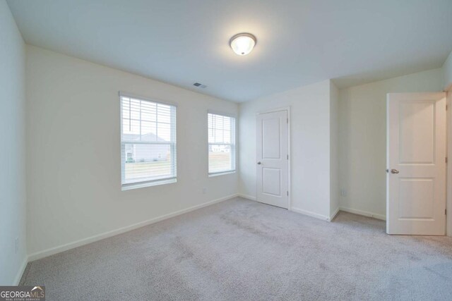 unfurnished bedroom featuring light colored carpet and a closet