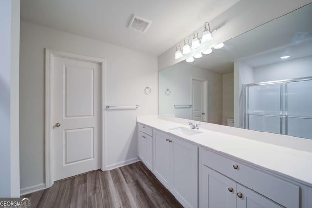 bathroom featuring vanity, wood-type flooring, and a shower with door