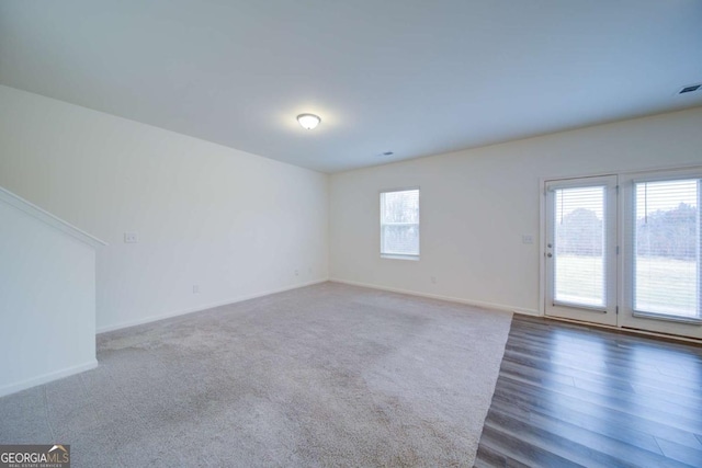 unfurnished room featuring dark wood-type flooring and a healthy amount of sunlight