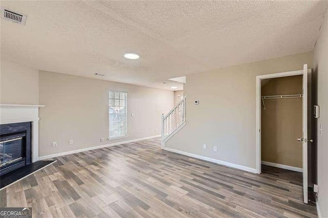 unfurnished living room featuring hardwood / wood-style floors and a textured ceiling