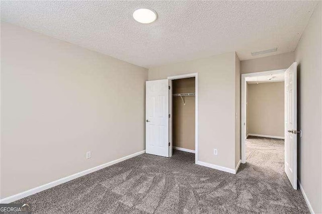 unfurnished bedroom with dark carpet, a textured ceiling, and a closet