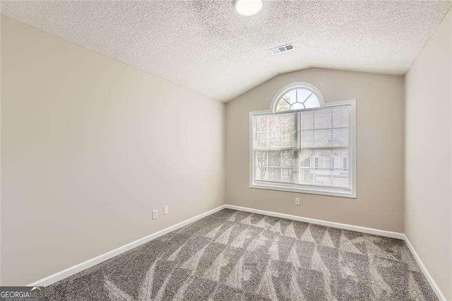 spare room featuring carpet flooring, a textured ceiling, and vaulted ceiling