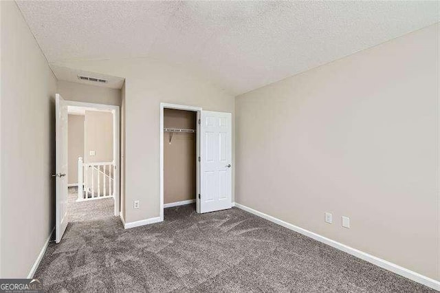 unfurnished bedroom featuring a closet, dark carpet, and a textured ceiling