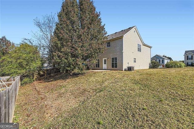 back of house featuring central AC unit and a yard