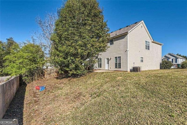 rear view of property with central air condition unit and a yard