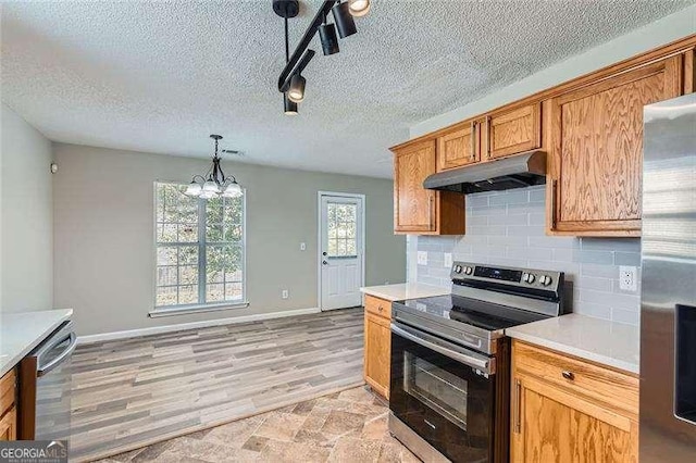 kitchen with appliances with stainless steel finishes, a textured ceiling, decorative light fixtures, a notable chandelier, and light hardwood / wood-style floors