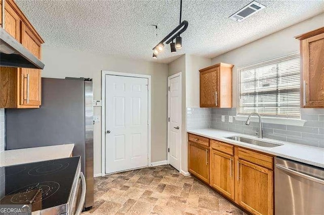 kitchen featuring dishwasher, rail lighting, sink, stove, and extractor fan