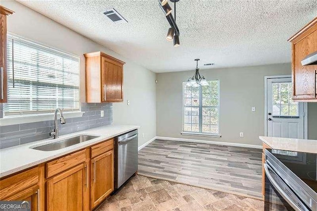 kitchen featuring stainless steel dishwasher, sink, an inviting chandelier, light hardwood / wood-style floors, and hanging light fixtures