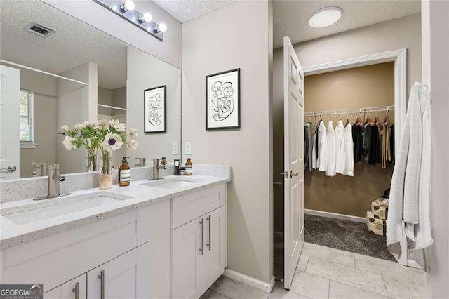 bathroom featuring tile patterned floors, vanity, and a textured ceiling