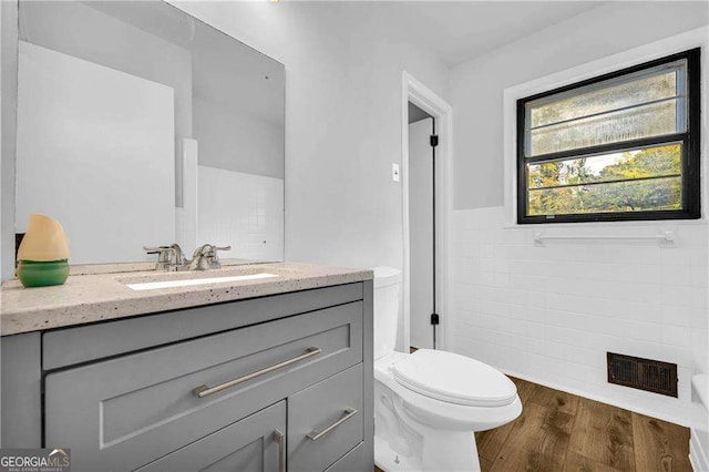 bathroom featuring vanity, wood-type flooring, tile walls, and toilet