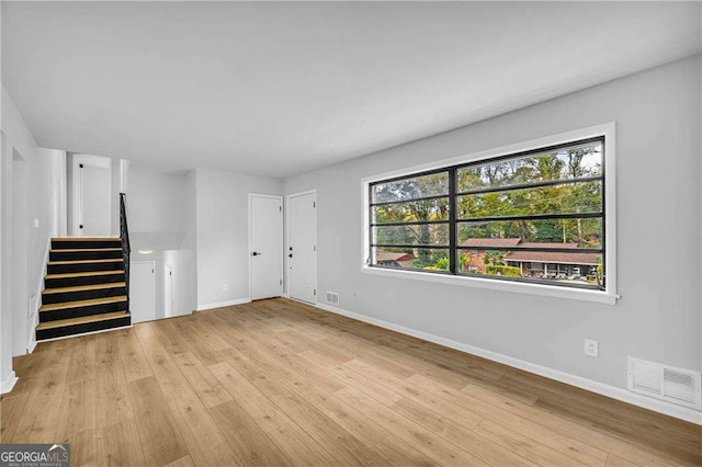 unfurnished living room featuring light wood-type flooring and a wealth of natural light