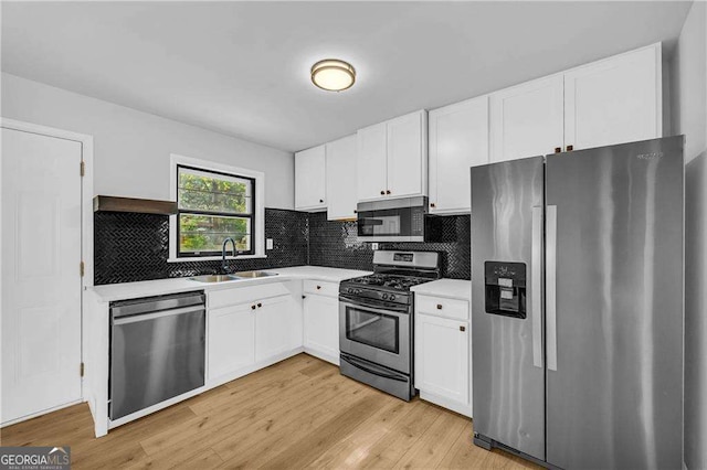 kitchen with sink, white cabinets, light wood-type flooring, and appliances with stainless steel finishes