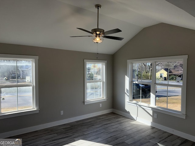 spare room featuring baseboards, dark wood-style floors, a ceiling fan, and vaulted ceiling