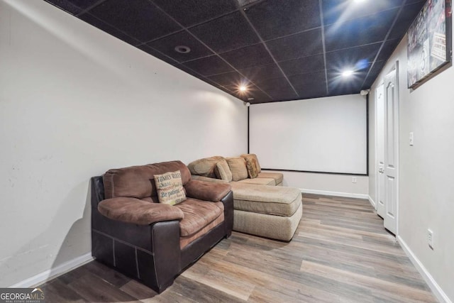 cinema room with a drop ceiling and hardwood / wood-style flooring