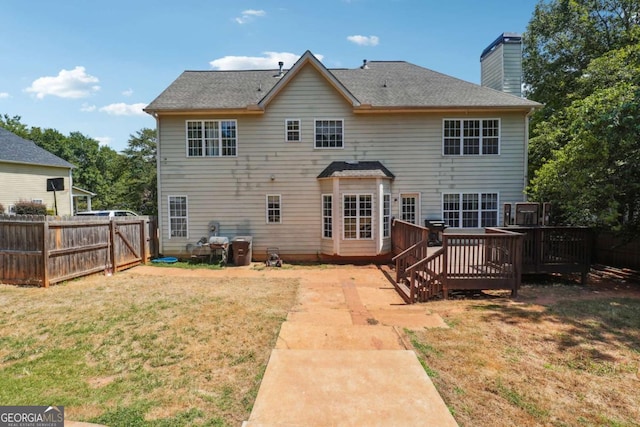 rear view of property featuring a yard and a deck