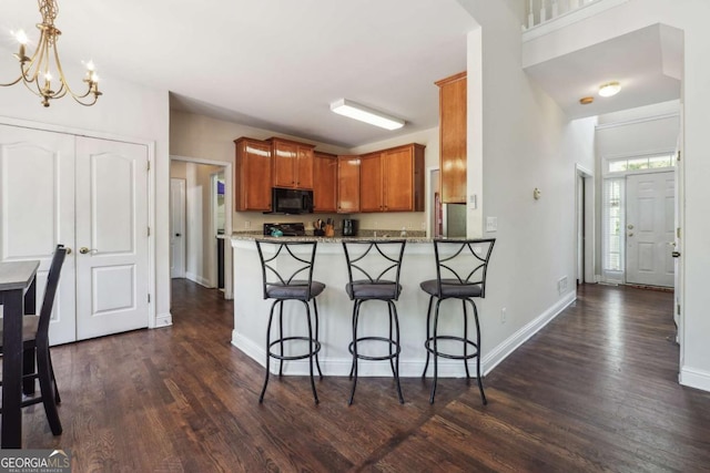 kitchen with kitchen peninsula, a breakfast bar, dark wood-type flooring, and black appliances