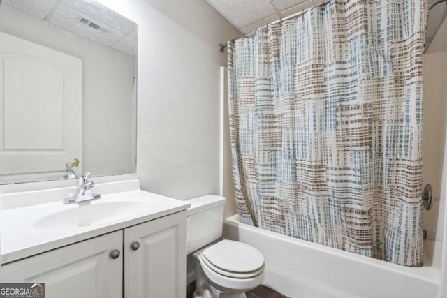 full bathroom with shower / bath combo with shower curtain, a drop ceiling, vanity, and toilet