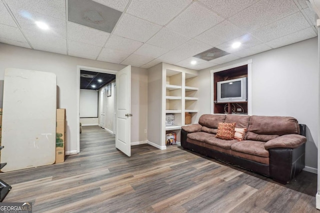 living room with a paneled ceiling and dark hardwood / wood-style floors