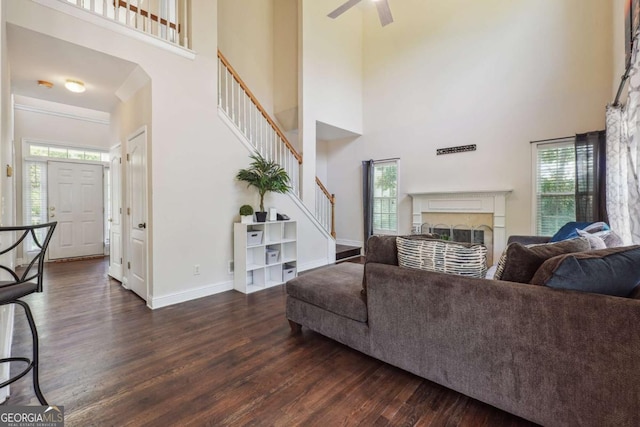 living room with ceiling fan, a towering ceiling, and dark wood-type flooring