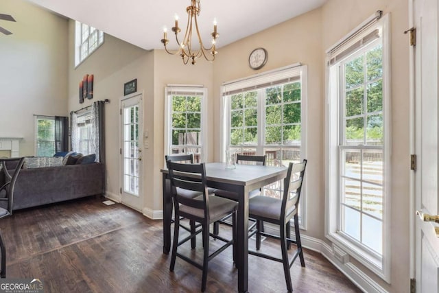 dining room with dark hardwood / wood-style flooring, a healthy amount of sunlight, and a notable chandelier