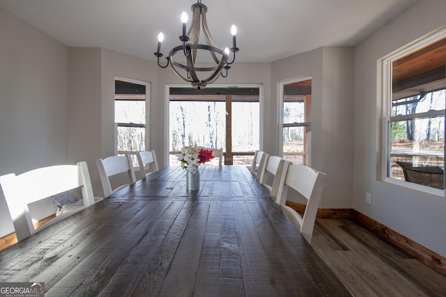 dining area featuring a healthy amount of sunlight, dark hardwood / wood-style flooring, and an inviting chandelier