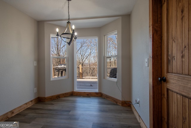 unfurnished dining area featuring a chandelier and dark hardwood / wood-style floors