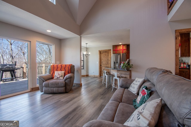 living room with wood-type flooring, an inviting chandelier, and high vaulted ceiling