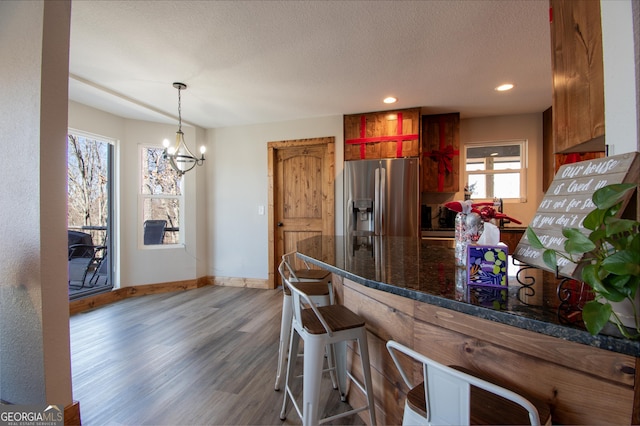 kitchen with stainless steel fridge with ice dispenser, dark hardwood / wood-style flooring, a notable chandelier, a textured ceiling, and decorative light fixtures