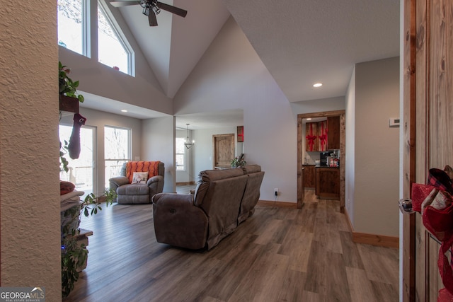 living room with high vaulted ceiling, wood-type flooring, and ceiling fan with notable chandelier