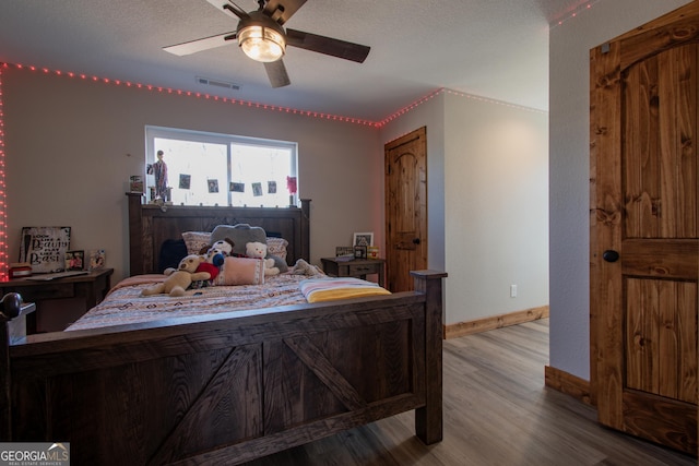 bedroom with ceiling fan, light hardwood / wood-style floors, and a textured ceiling