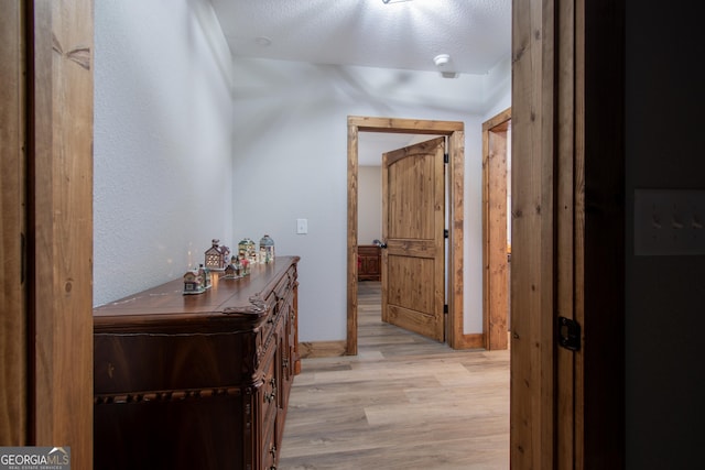 hallway with a textured ceiling and light wood-type flooring