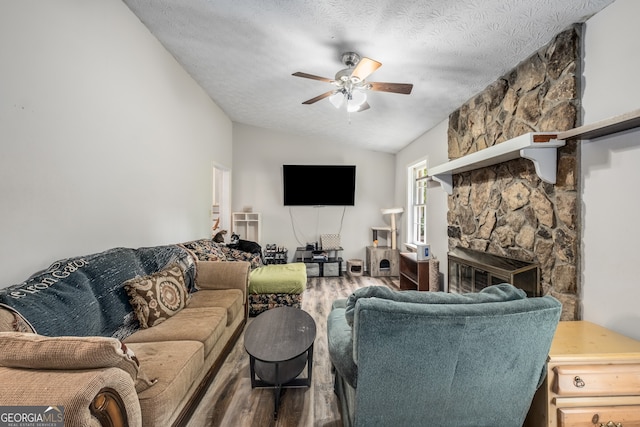 living room featuring a textured ceiling, a fireplace, vaulted ceiling, and hardwood / wood-style flooring