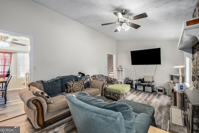 living room featuring a textured ceiling, hardwood / wood-style flooring, vaulted ceiling, and ceiling fan