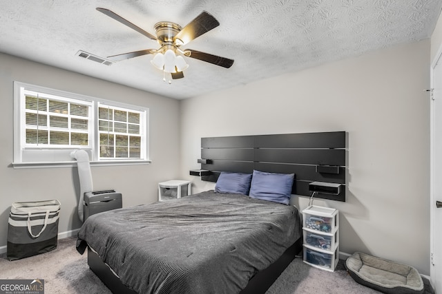 carpeted bedroom with ceiling fan and a textured ceiling