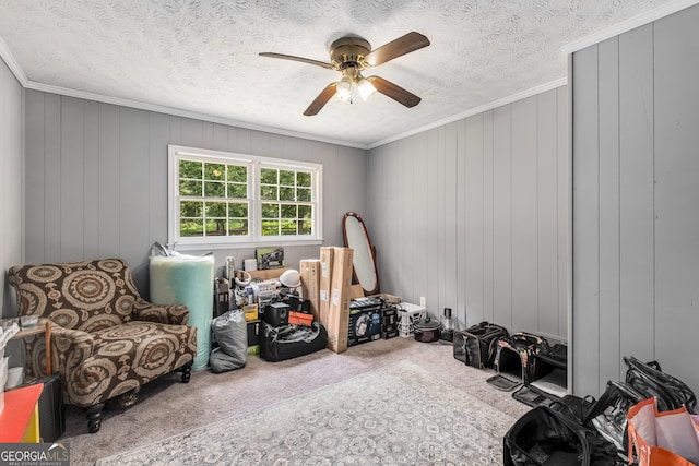 interior space featuring carpet, a textured ceiling, ceiling fan, crown molding, and wood walls