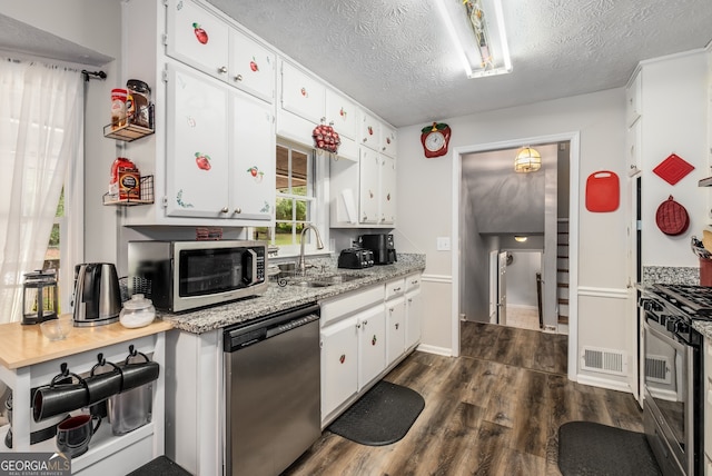 kitchen with sink, dark wood-type flooring, stainless steel appliances, a textured ceiling, and white cabinets