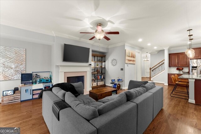 living room featuring hardwood / wood-style floors, ceiling fan, and ornamental molding