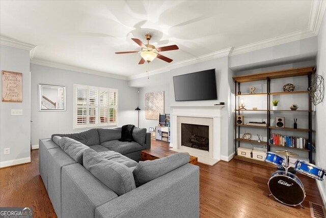 living room featuring hardwood / wood-style floors, a healthy amount of sunlight, ornamental molding, and a fireplace