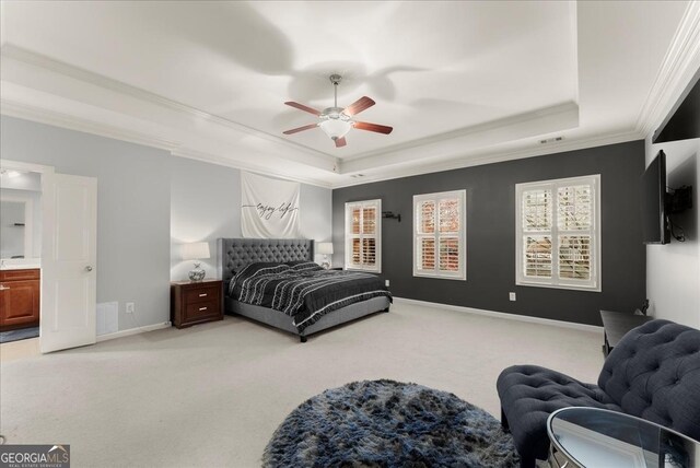 carpeted bedroom with a tray ceiling, ceiling fan, crown molding, and ensuite bathroom